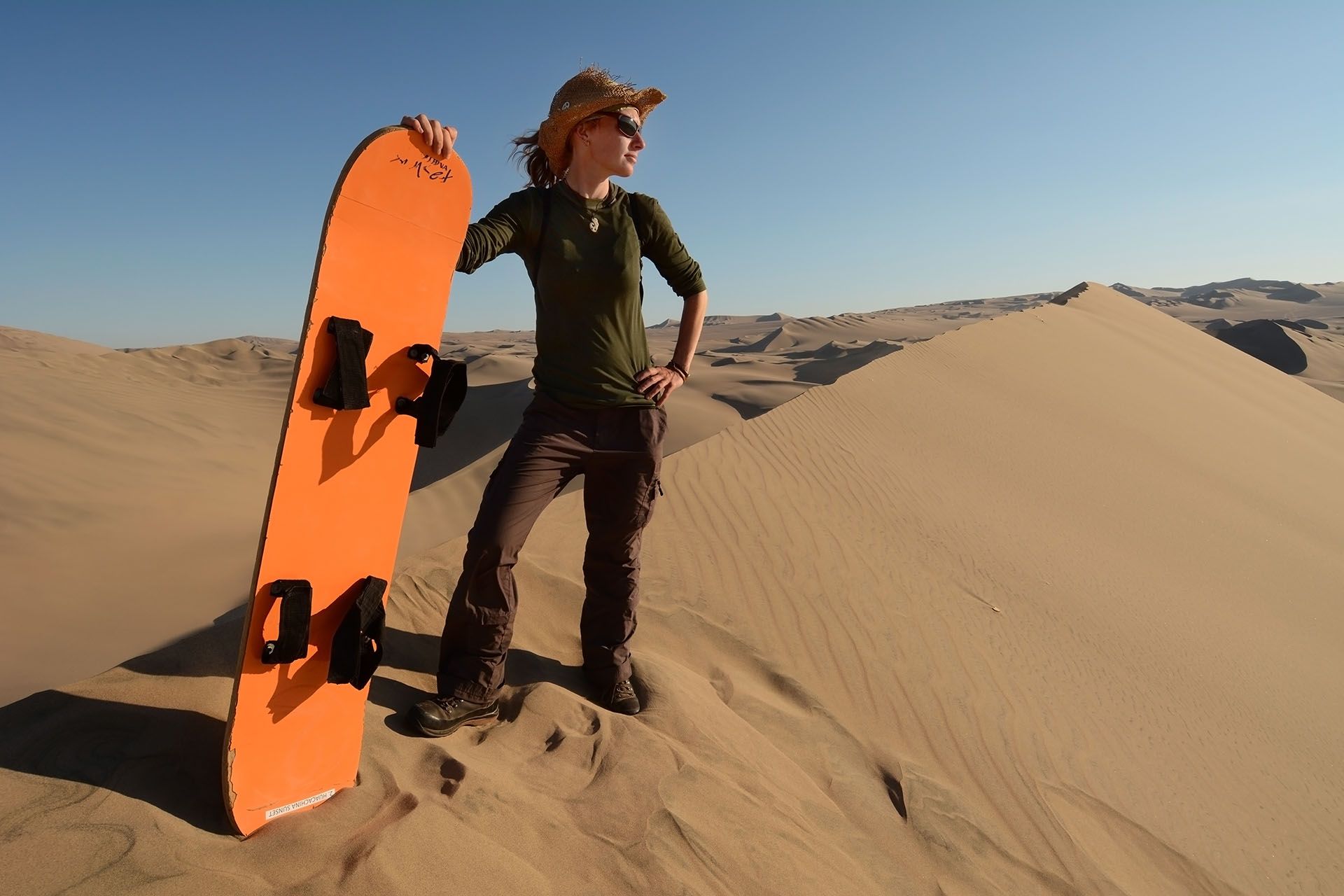 Young woman posing with the sandboard, Oasis of Huacachina, Atacama Desert, Peru