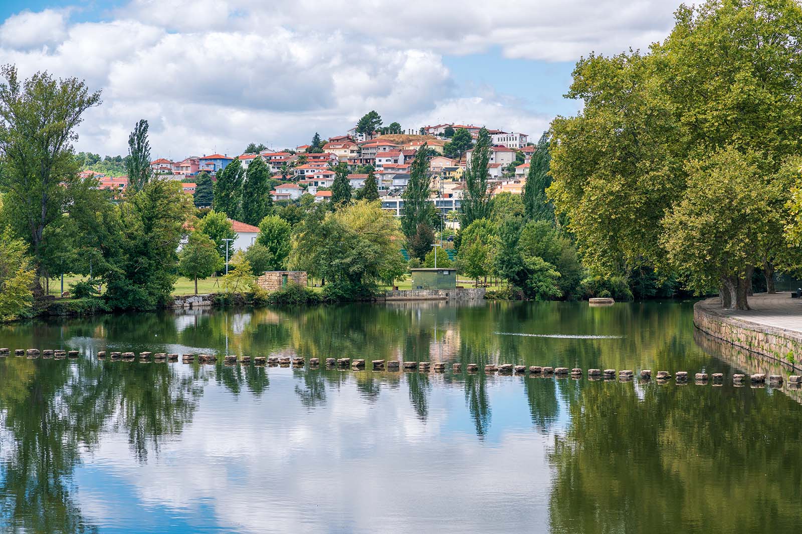 Támega River, calm water, leisure place, stone pass over the river. Chavez cityscape with leafy trees. Relaxation landscape © Shutterstock