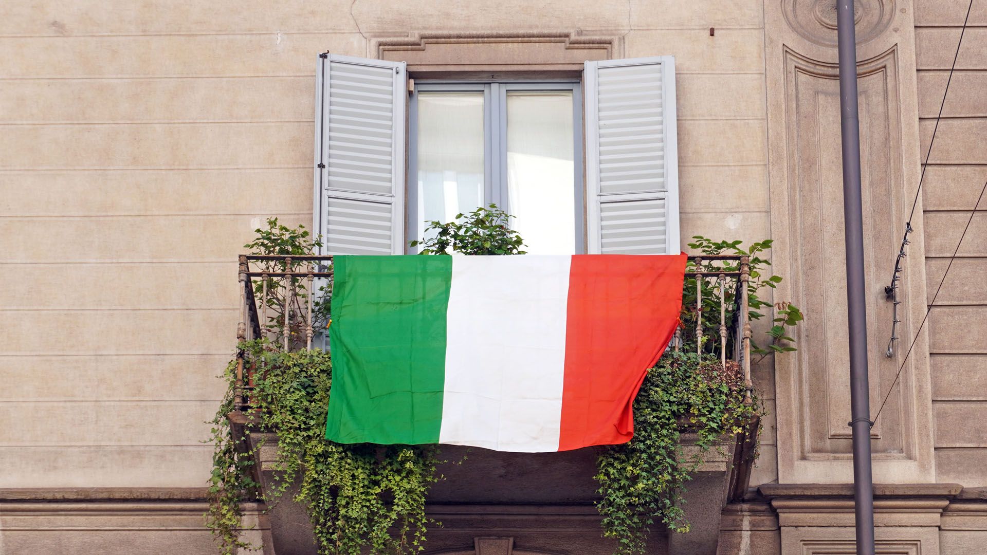 Flag of Italy hanging on the balcony in Milan, Italy © DELBO ANDREA/Shutterstock