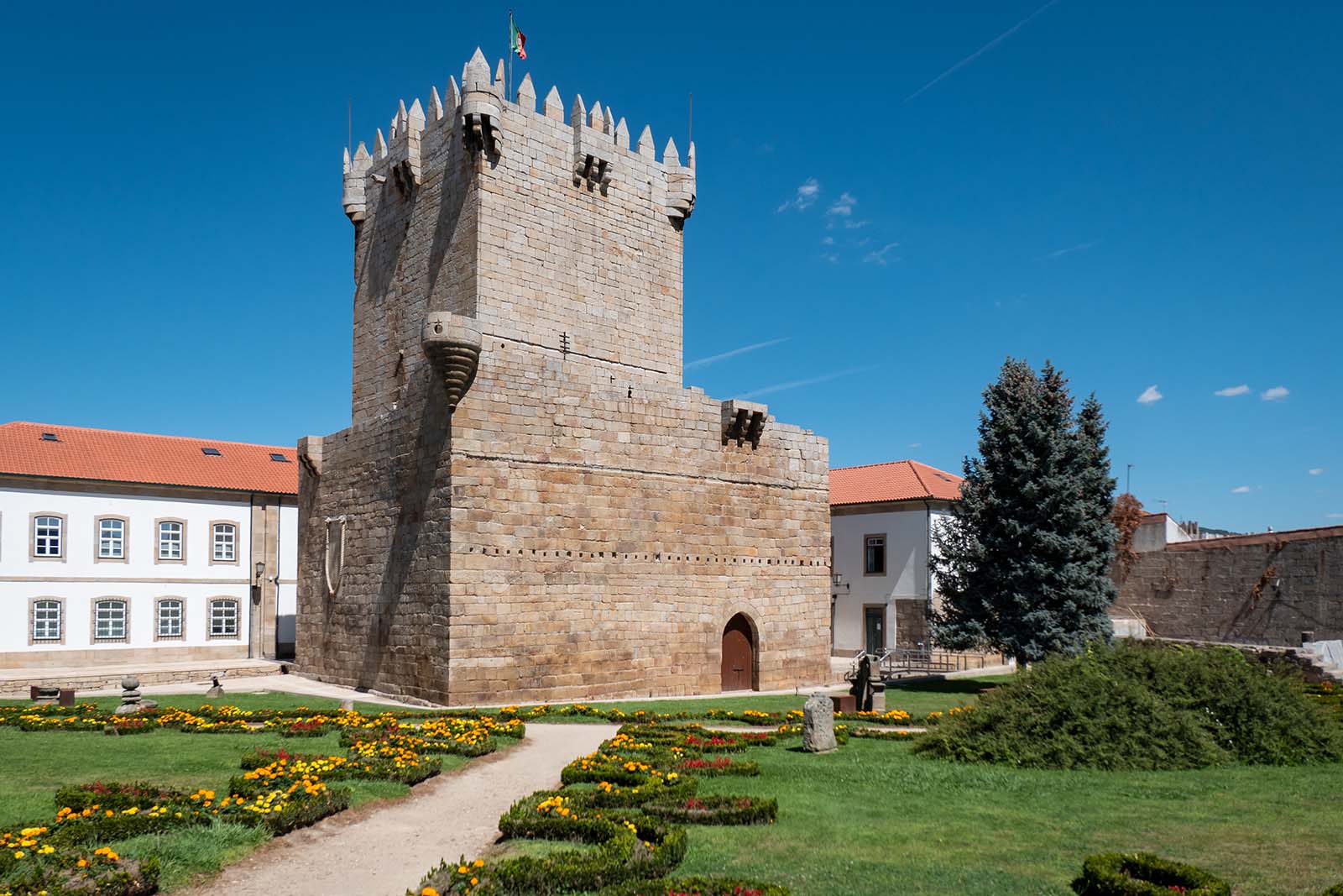 Keep or Chaves Castle with the Portuguese flag at the top and a beautiful garden in front in Portugal © Shutterstock