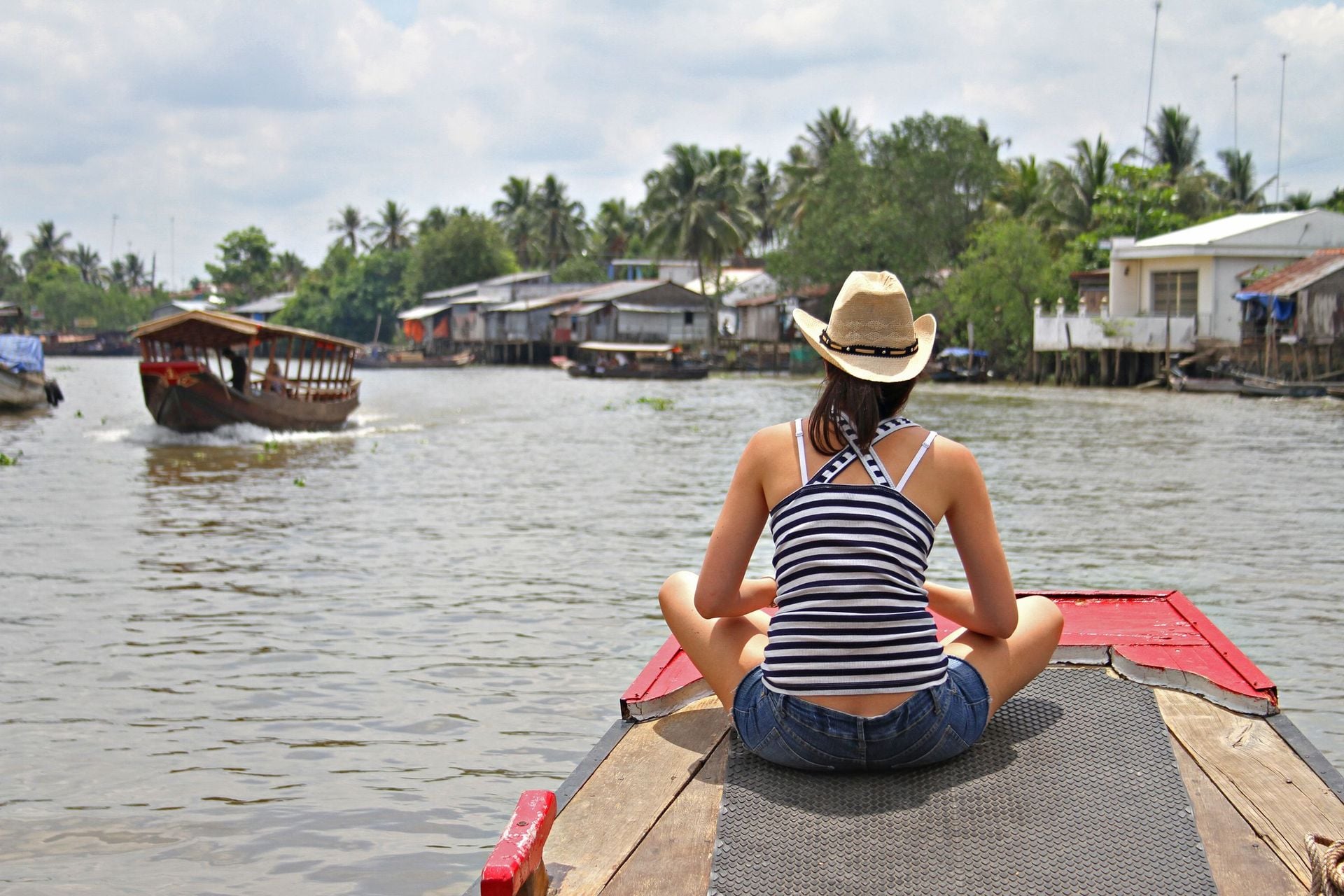 A young woman in a straw hat rides a boat up the Mekong River in Vietnam.