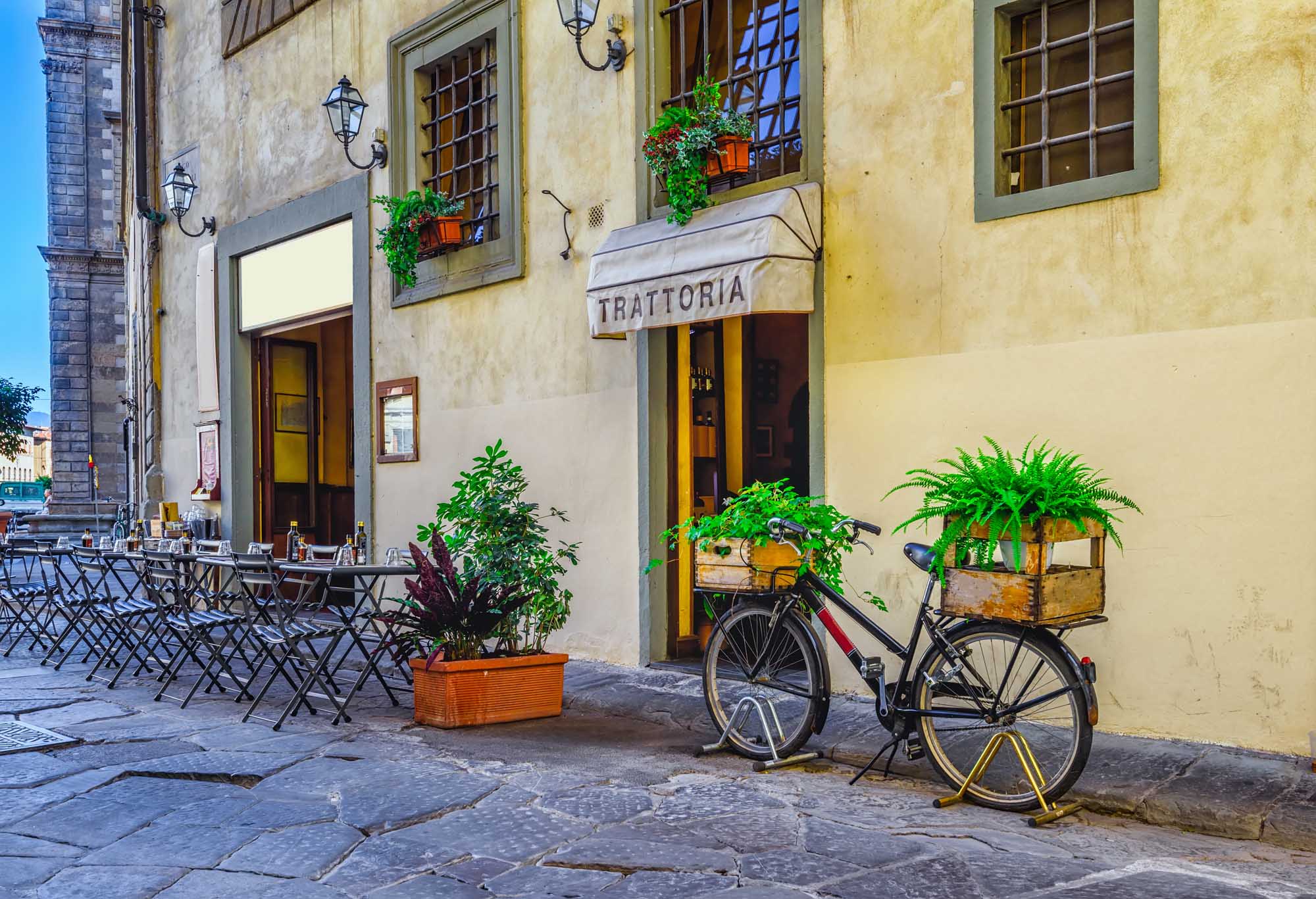Narrow street with tables of old trattoria in Florence, Tuscany, Italy.