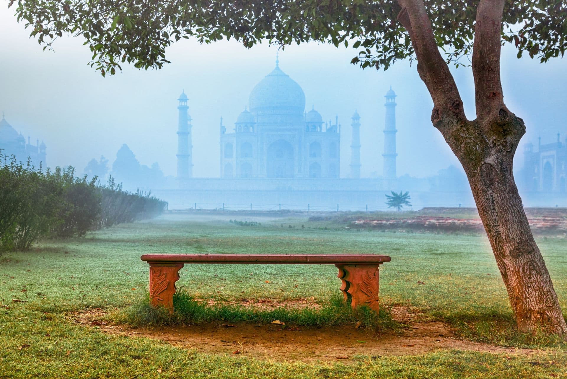 Empty bench by Taj Mahal hidden in morning fog