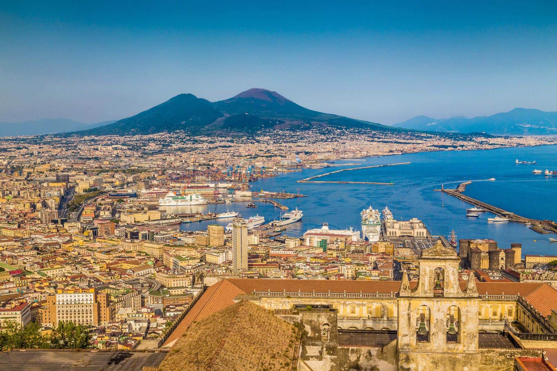 Scenic picture-postcard view of the city of Napoli (Naples) with famous Mount Vesuvius in the background in golden evening light at sunset, Campania, Italy