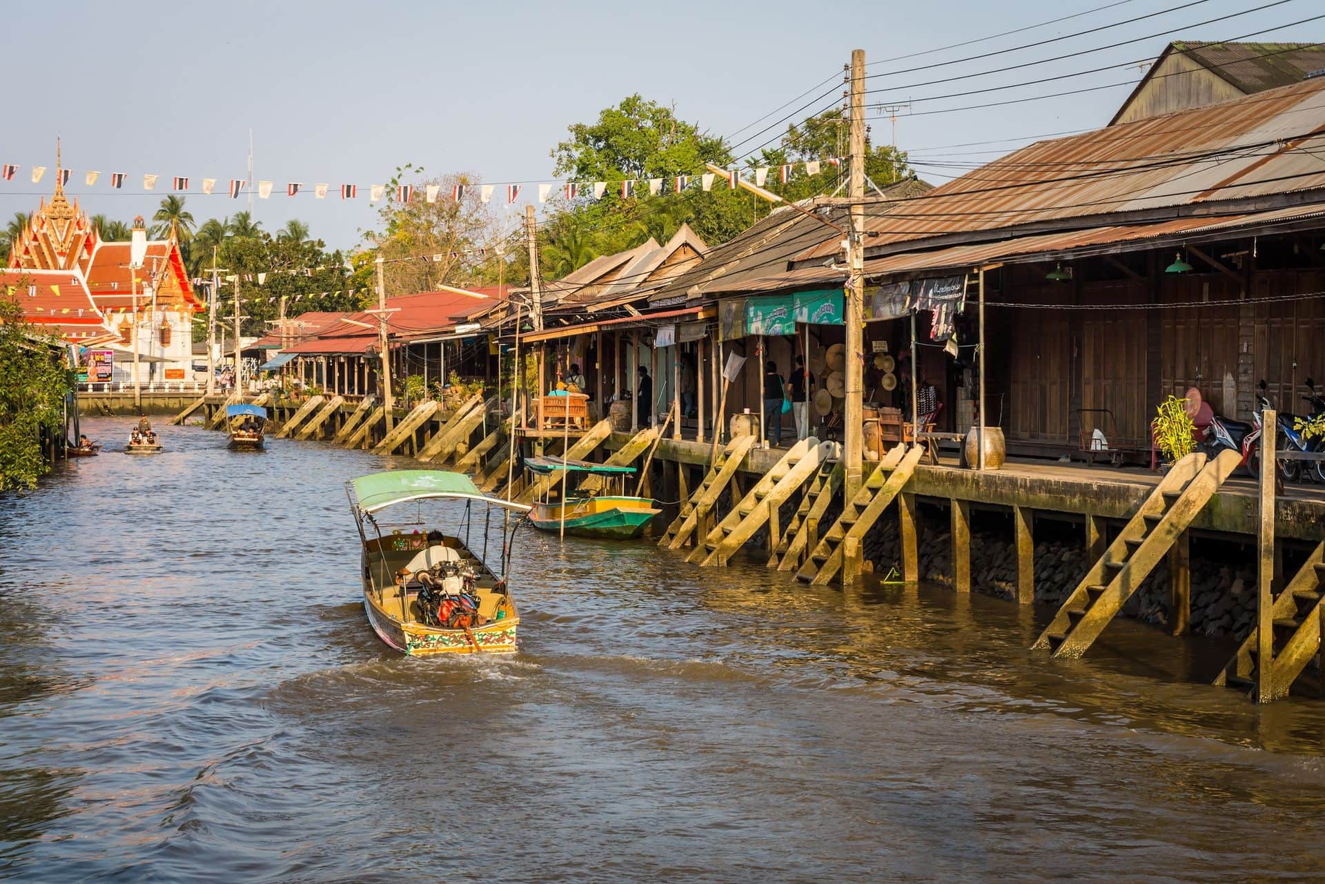 The traditional vintage motorboat and riverside Thai village at Amphawa district in countryside of Thailand