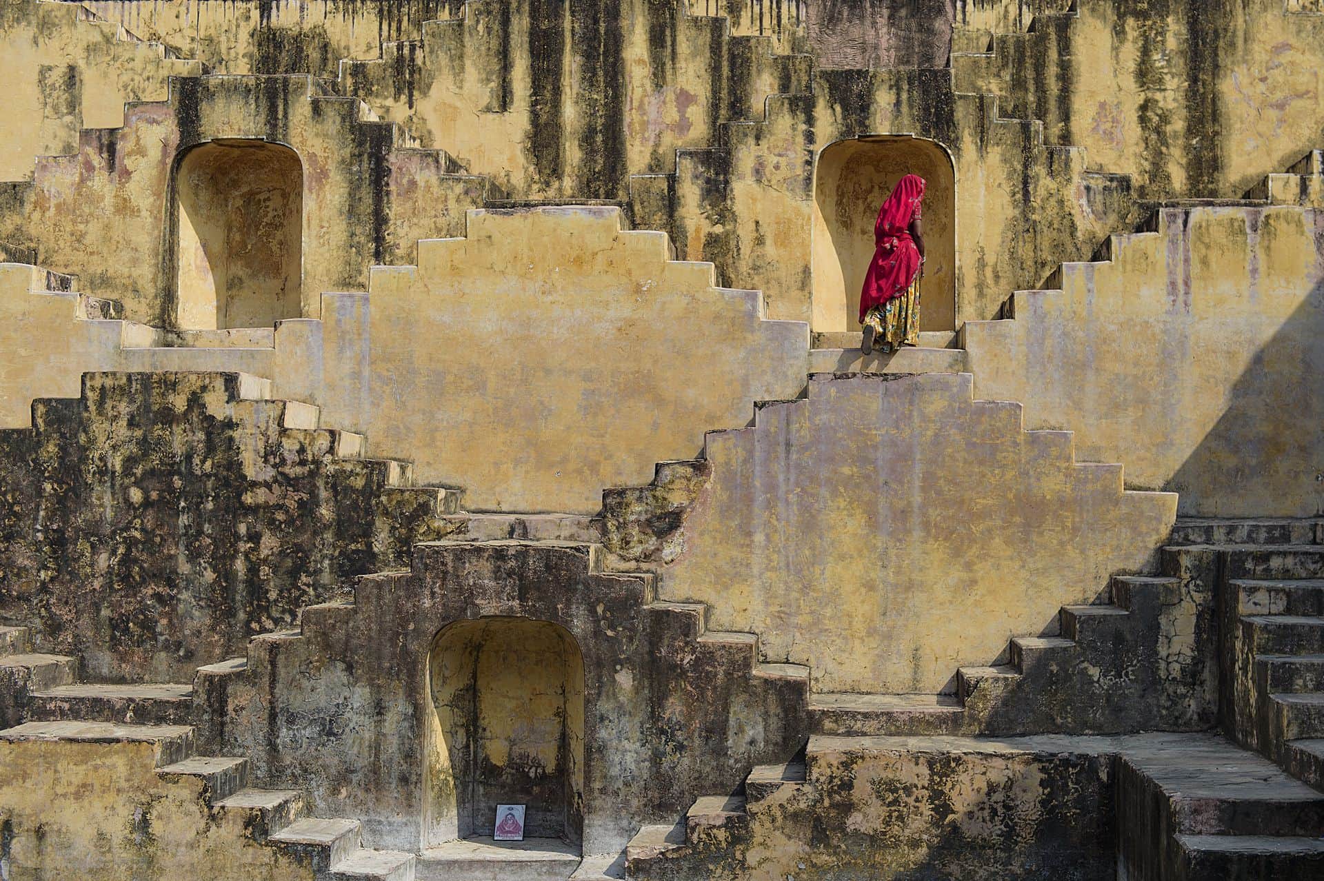 Local Women crossing the stepwells of Chand Baori, in Jaipur, India. It was built as a monument to the goddess of joy and happiness, Hashat Mata.