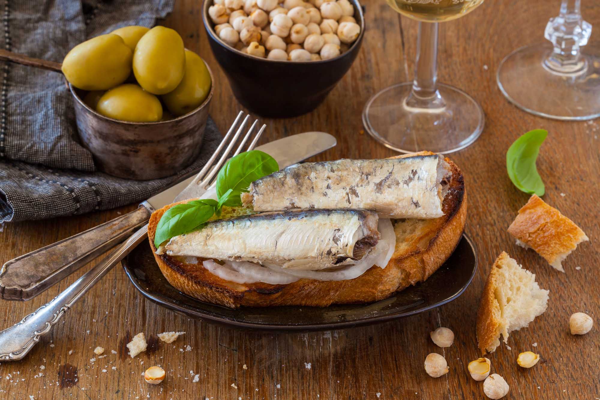 Toast with sardines, olives and white wine served as appetizer or tapa.
