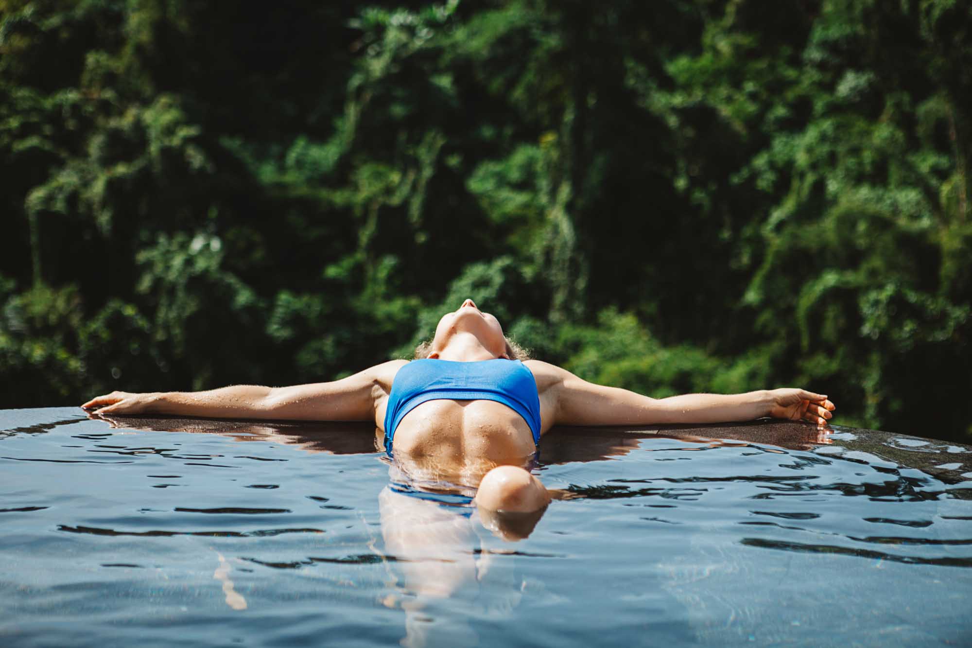 Young girl relaxing in the pool with jungle view during yoga retreat vacation in Bali