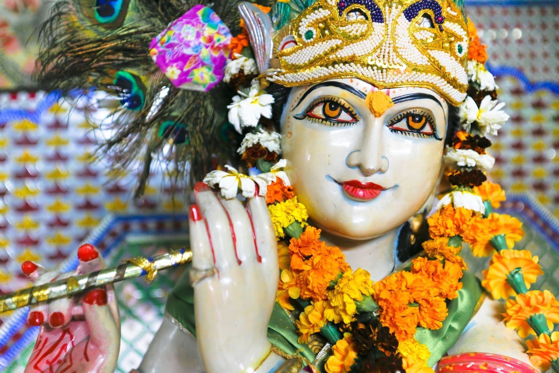 Statue of garlanded Hindu god Krishna playing flute in Delhi, India.