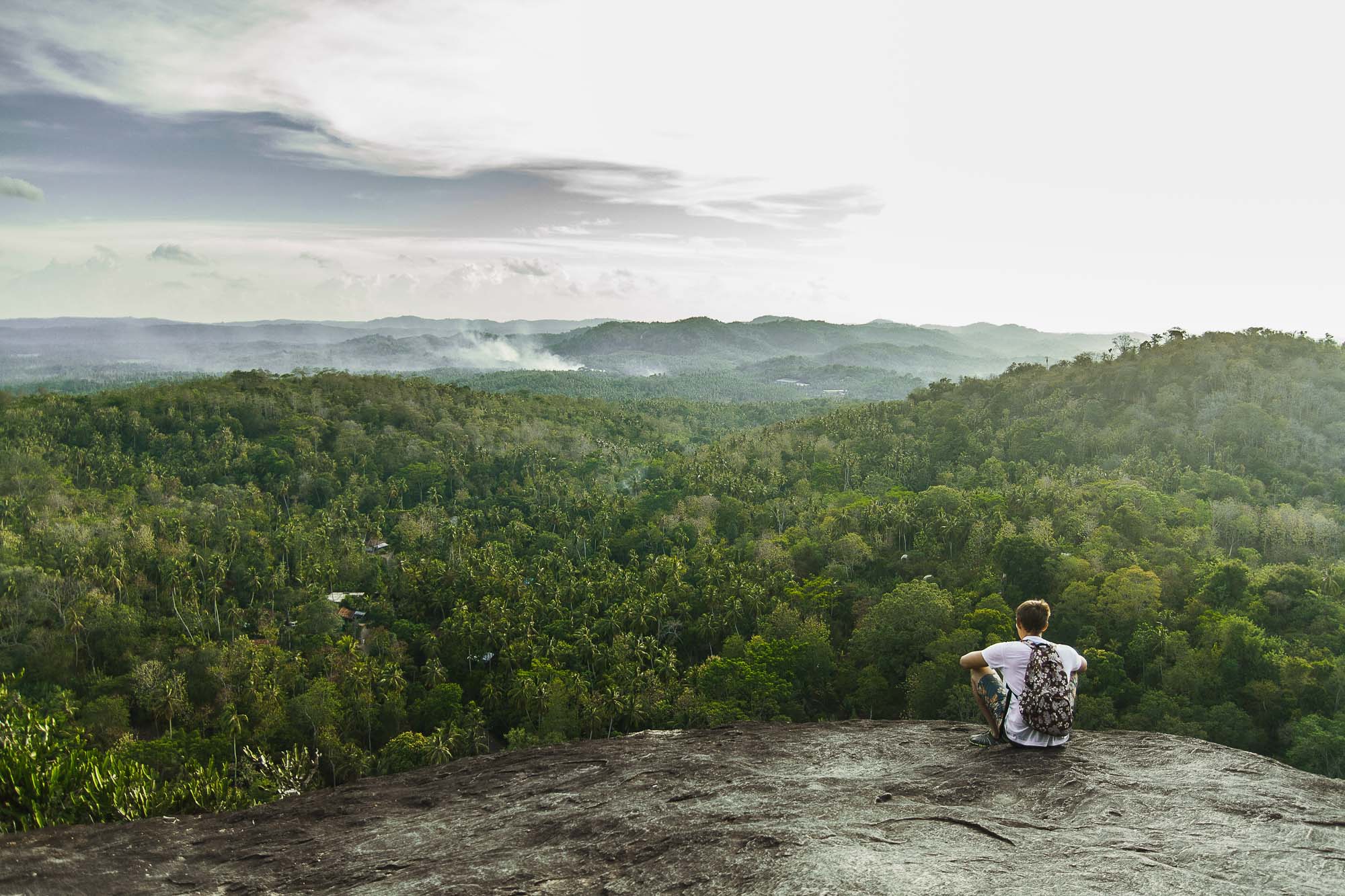 The young man / boy looks at the jungle on the viewing platform of the Mulgirigala Raja Maha Vihara, Sri Lanka