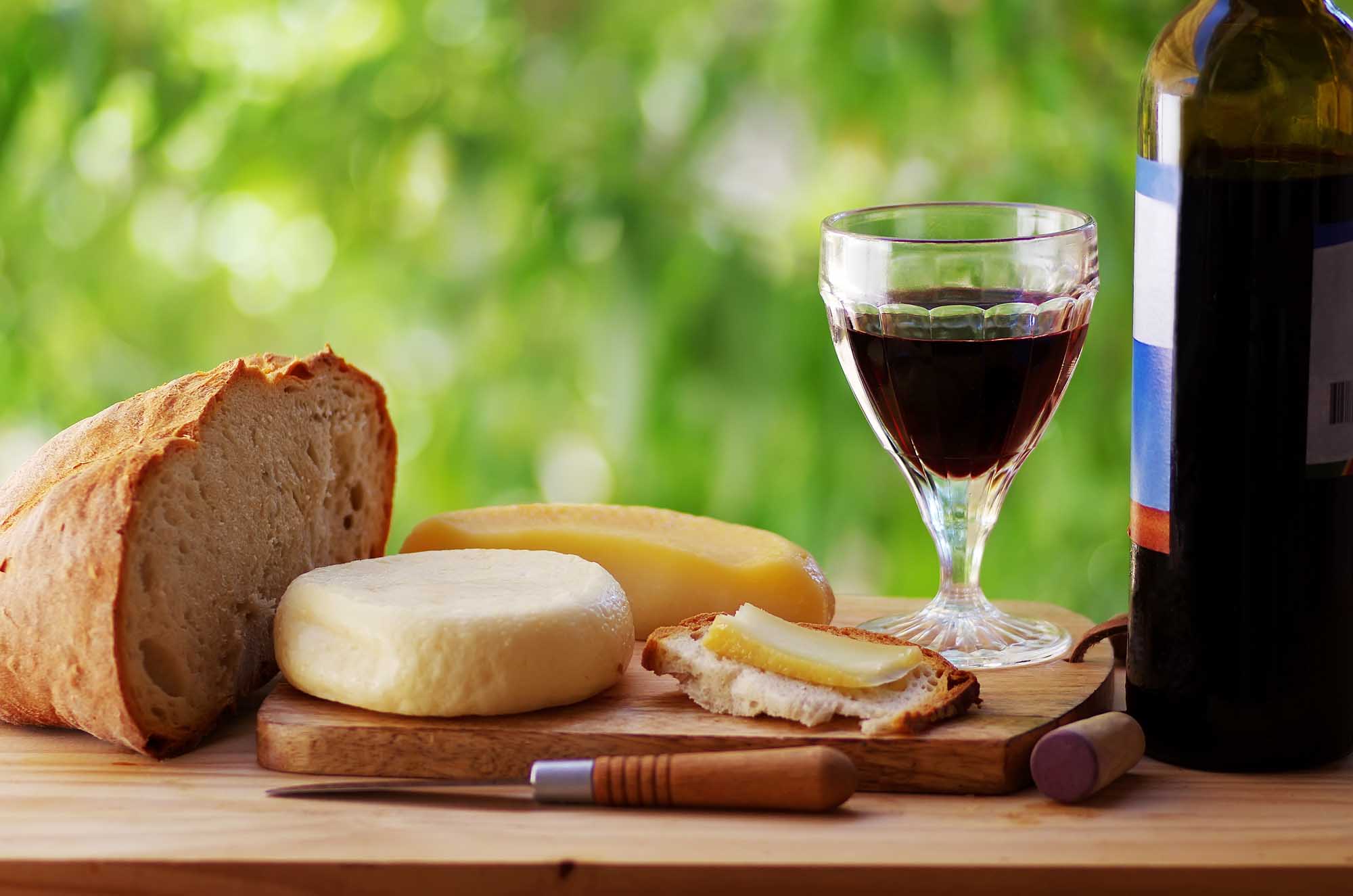 cheese, bread, and red wine on table