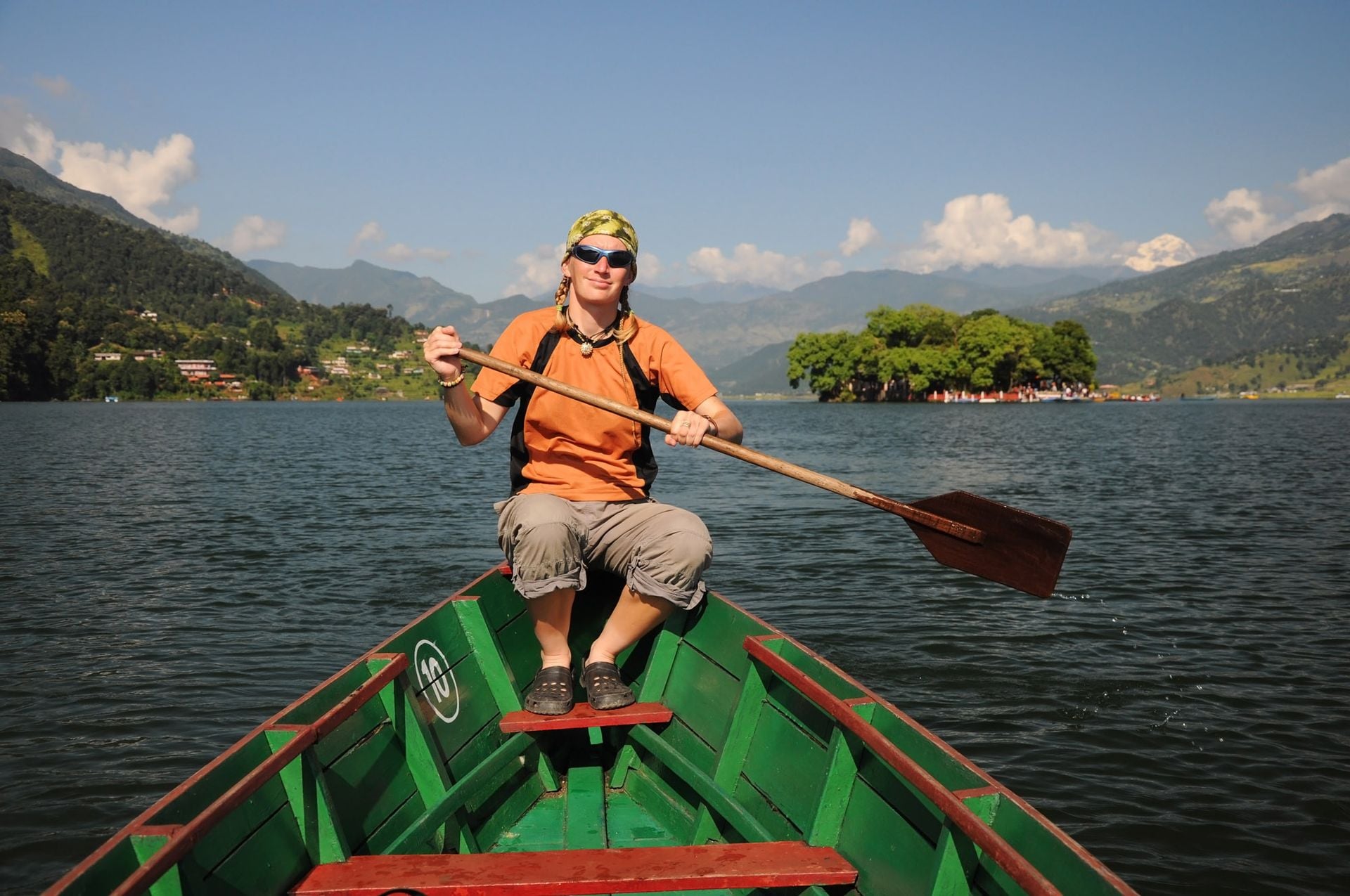 Young blond woman paddling on the boat, Phewa lake in Pokhara