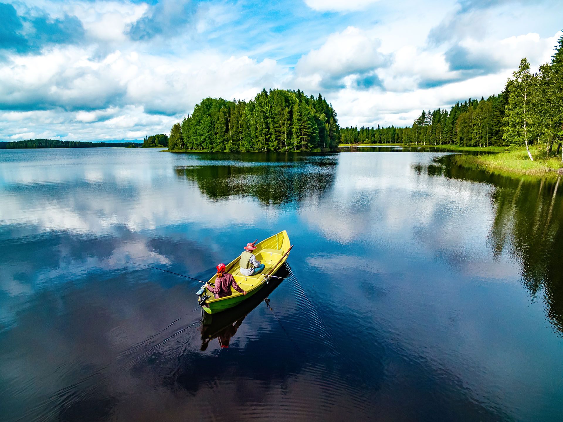 Aerial view of fishing boat with young woman and man in blue summer lake in Finland © Ekaterina Kondratova/Shutterstock